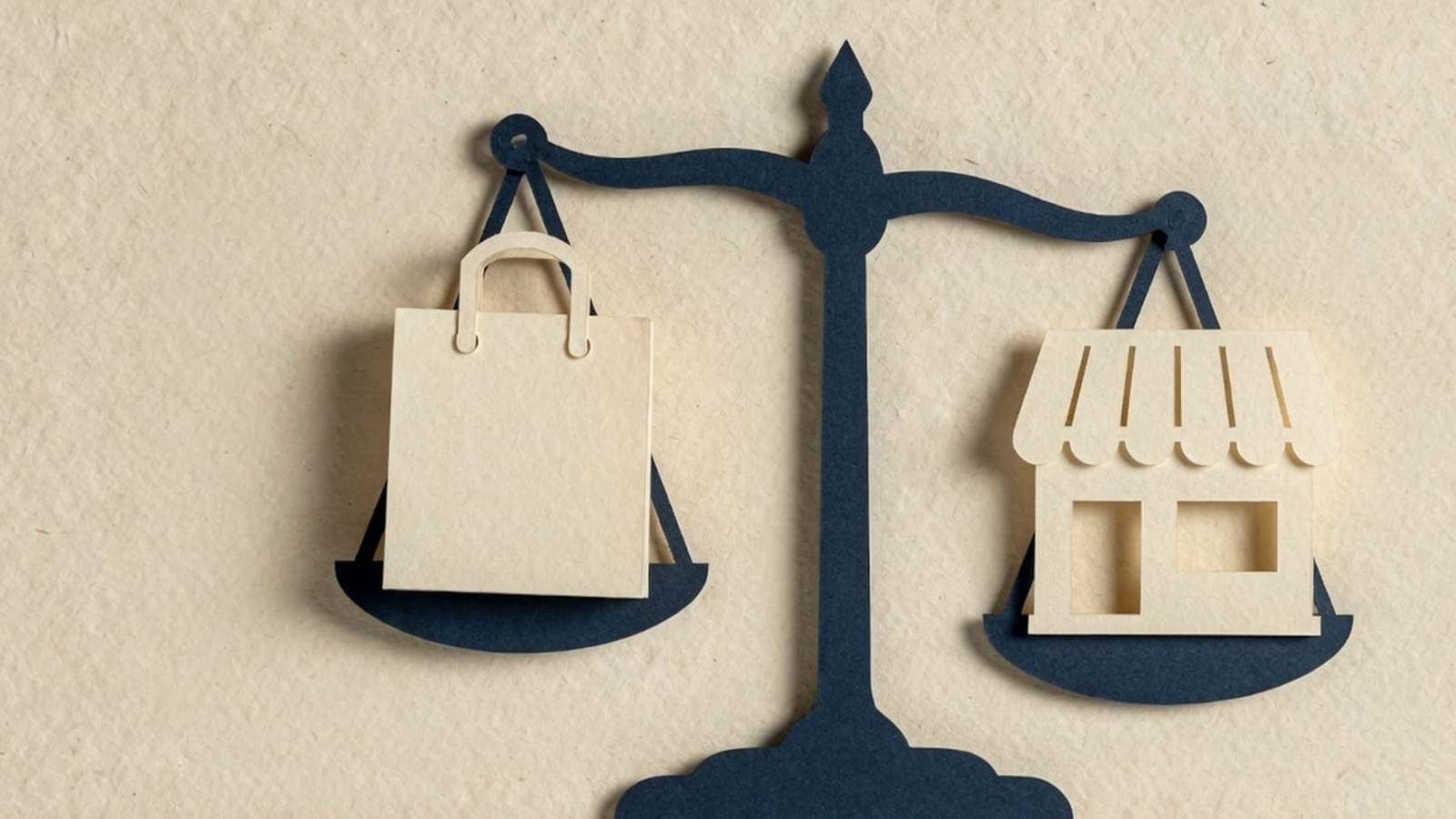 Paper-craft illustration: a navy balance scale with a cream shopping bag on one pan and a cream storefront on the other.